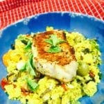 Curry Vegetable Couscous topped with a pork chop in a blue bowl.