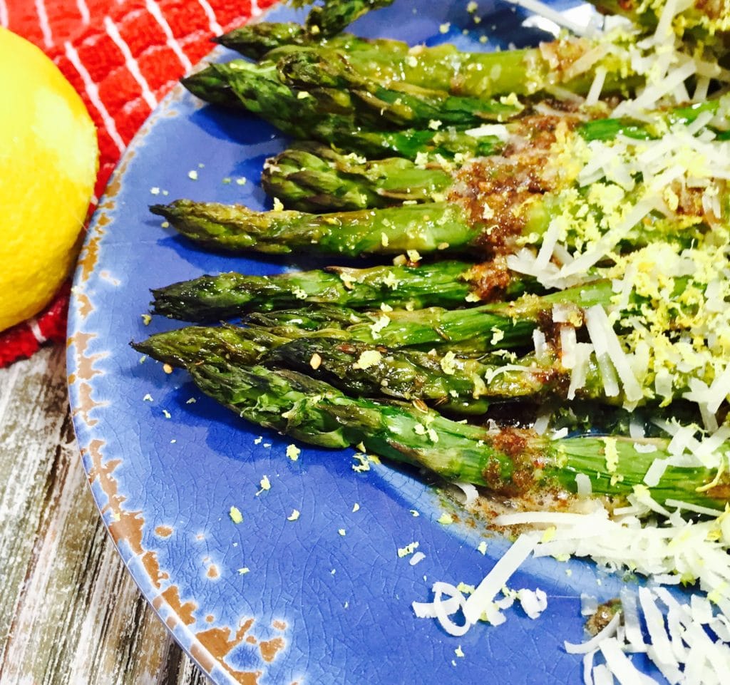 Cooked asparagus with browned butter on a blue plate