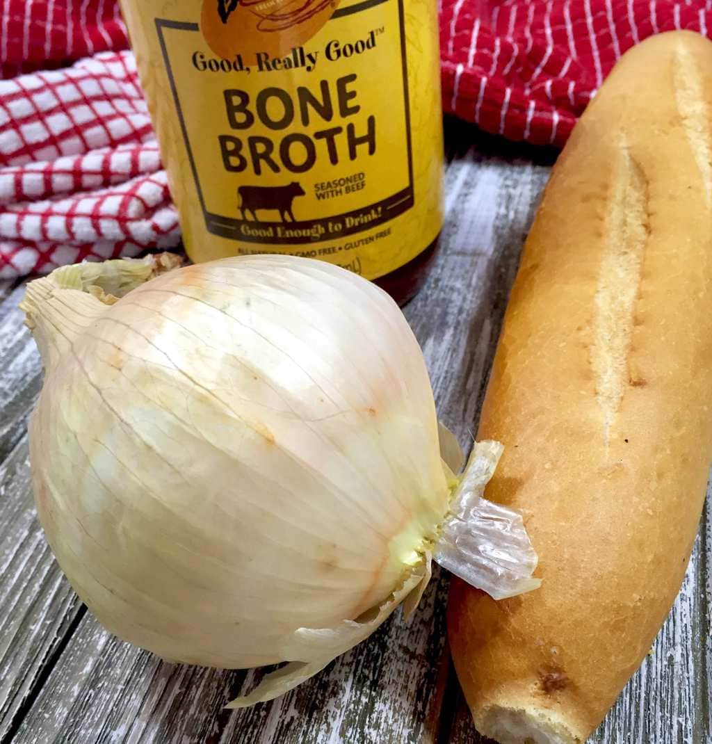 Yellow onion, Bone broth and French baguette on a wooden table