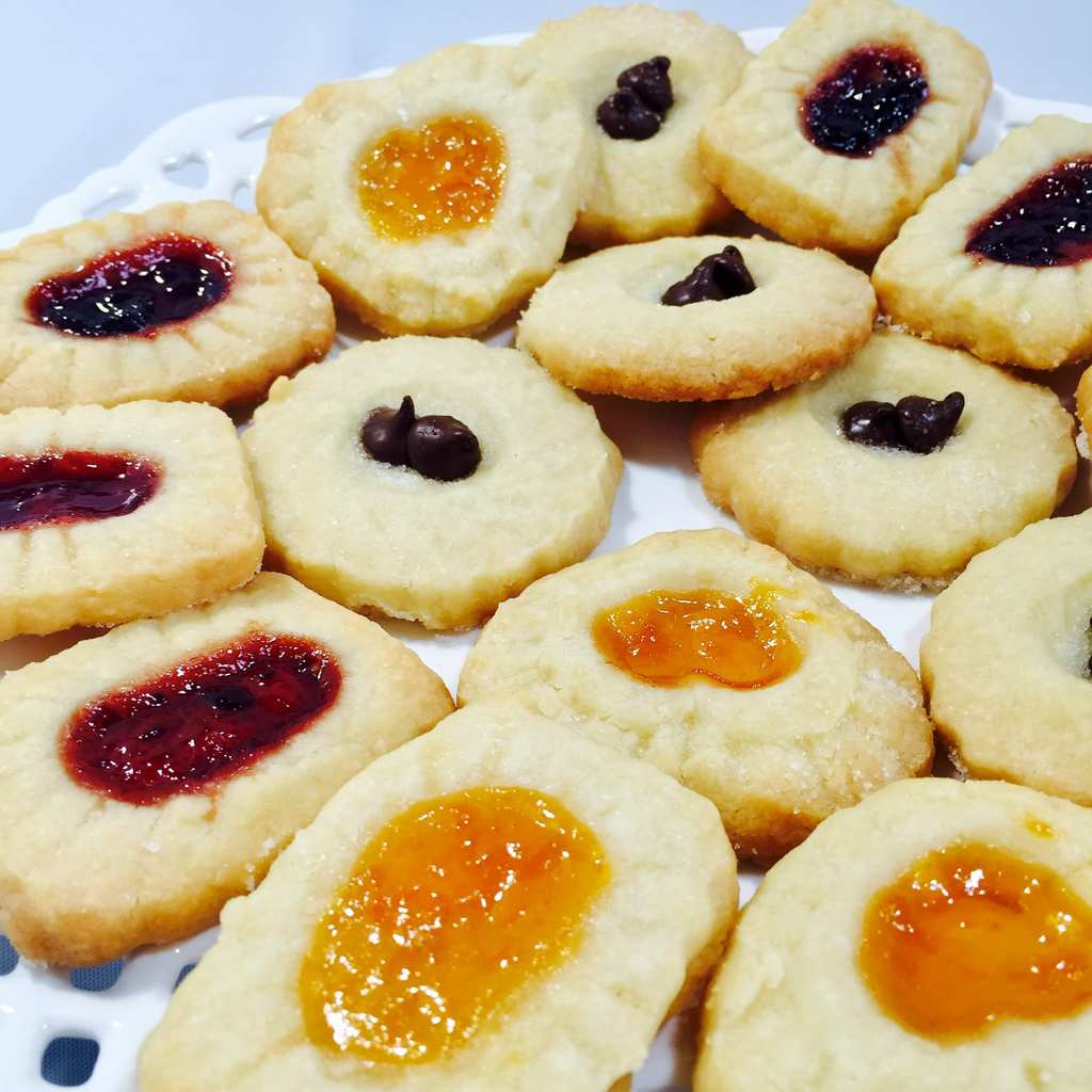 Baked jam filled shortbread cookies on a white plate