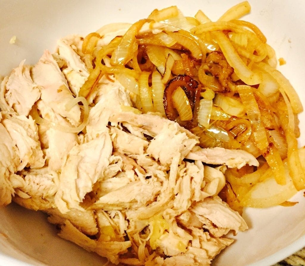 shredded chicken and browned onions in a white bowl