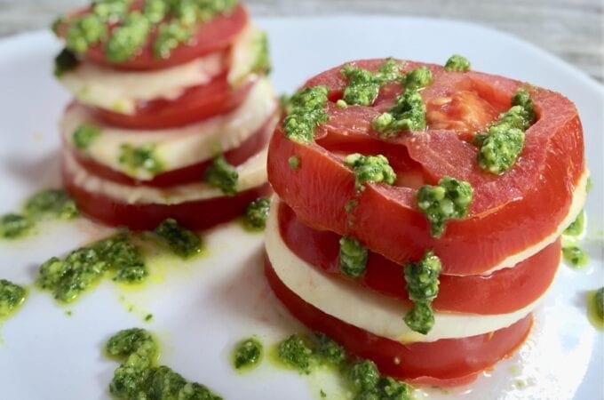 Stacked tomato salad with pesto on a white