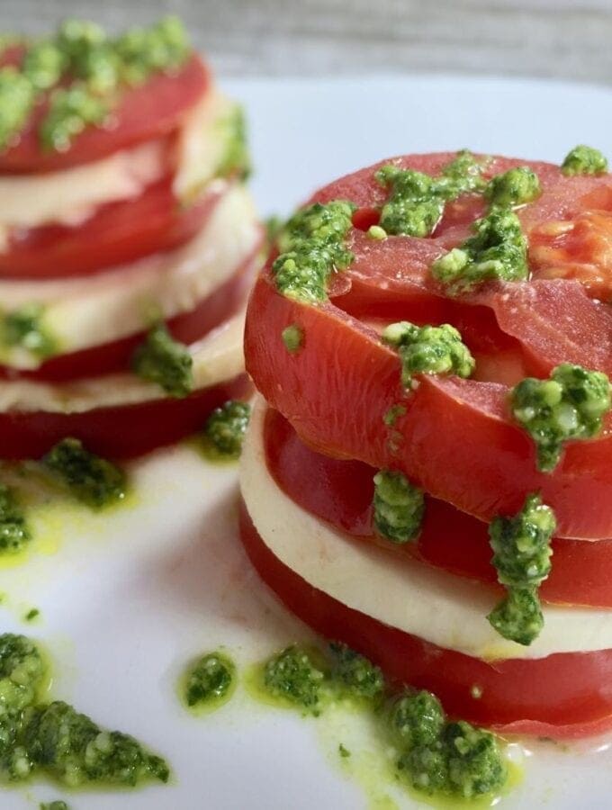 Stacked tomato salad with pesto on a white
