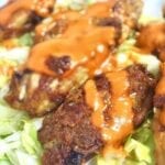 Crispy chicken wings with sauce over lettuce