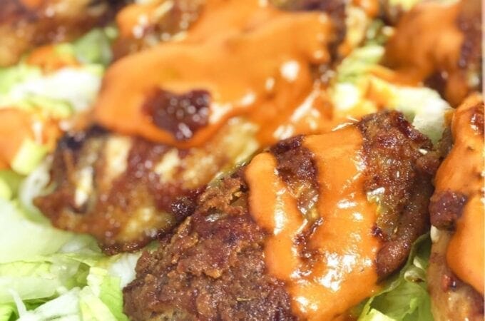 Crispy chicken wings with sauce over lettuce