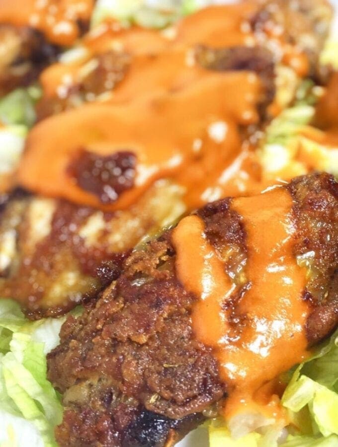 Crispy chicken wings with sauce over lettuce