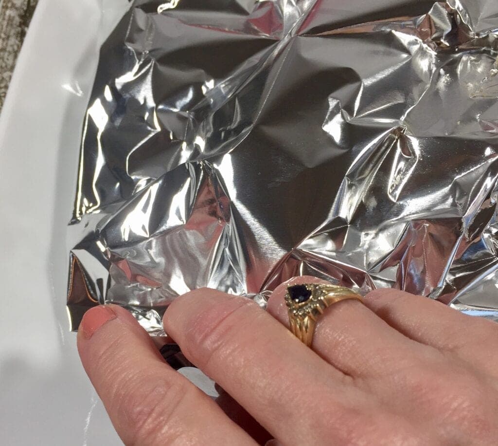 Hand folding a tin foil package