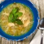 Chicken and vegetable soup in a blue bowl on a wooden table