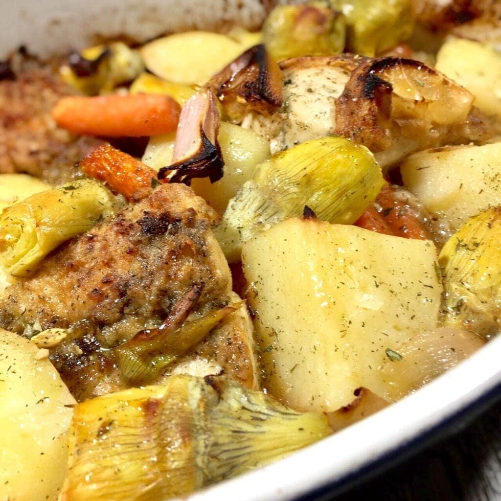 roasted lemon chicken with artichokes, potatoes and carrots in a white pan