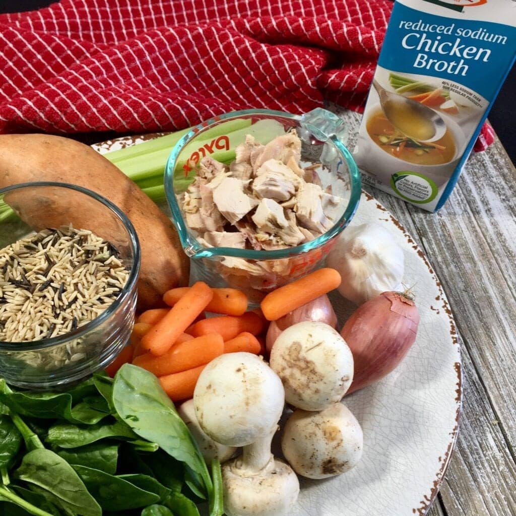 cooked chicken, yam, spinach, wild rice, spinach, carrots, shallots, garlic, celery and mushrooms on a white plate