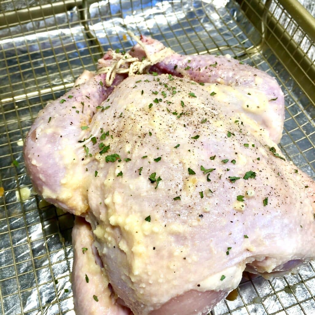 Chicken buttered and herbed and ready to be roasted on a rack 