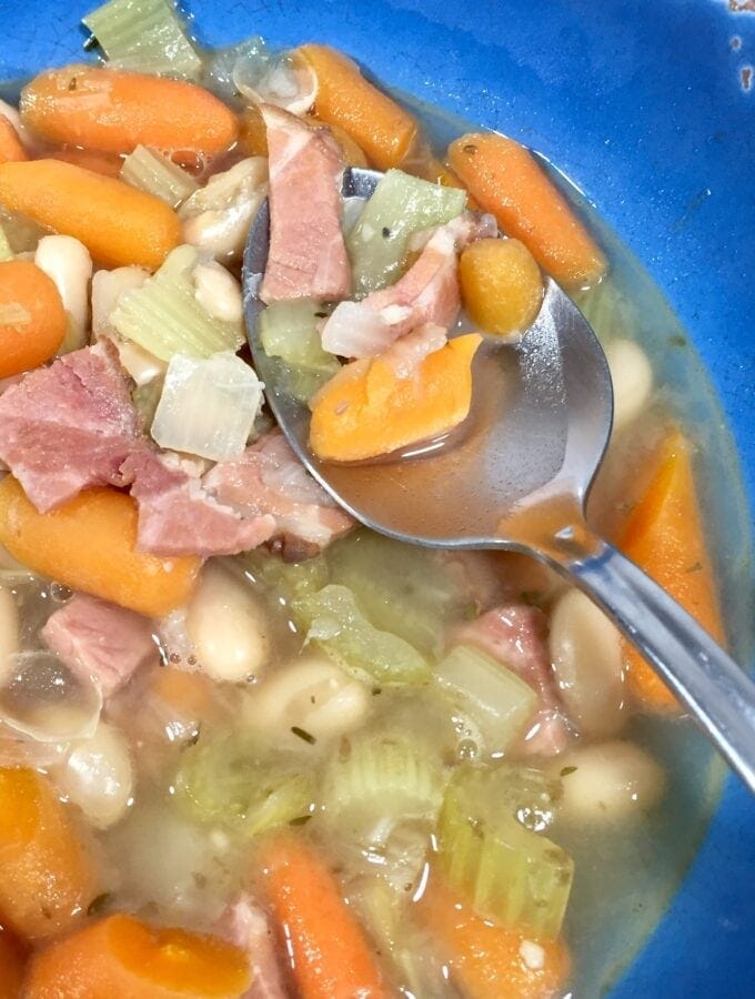 a bowl of Ham and Bean Soup pin a blue bowl with a spoon