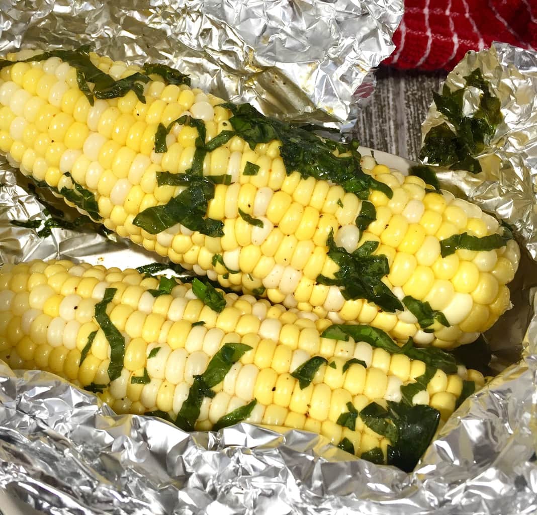Freshly steamed corn on the cob with basil