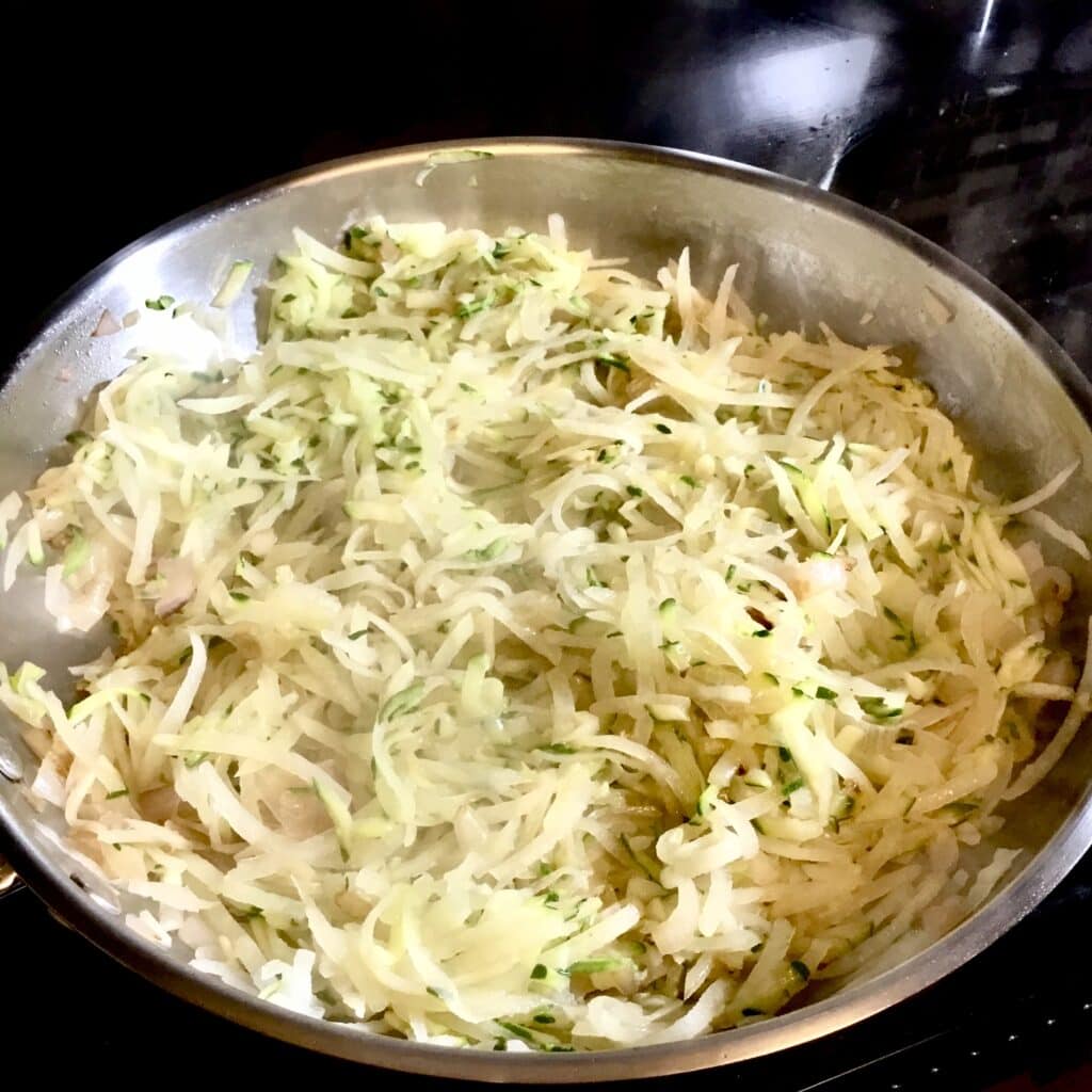 Shredded zucchini and potatoes in a frypan