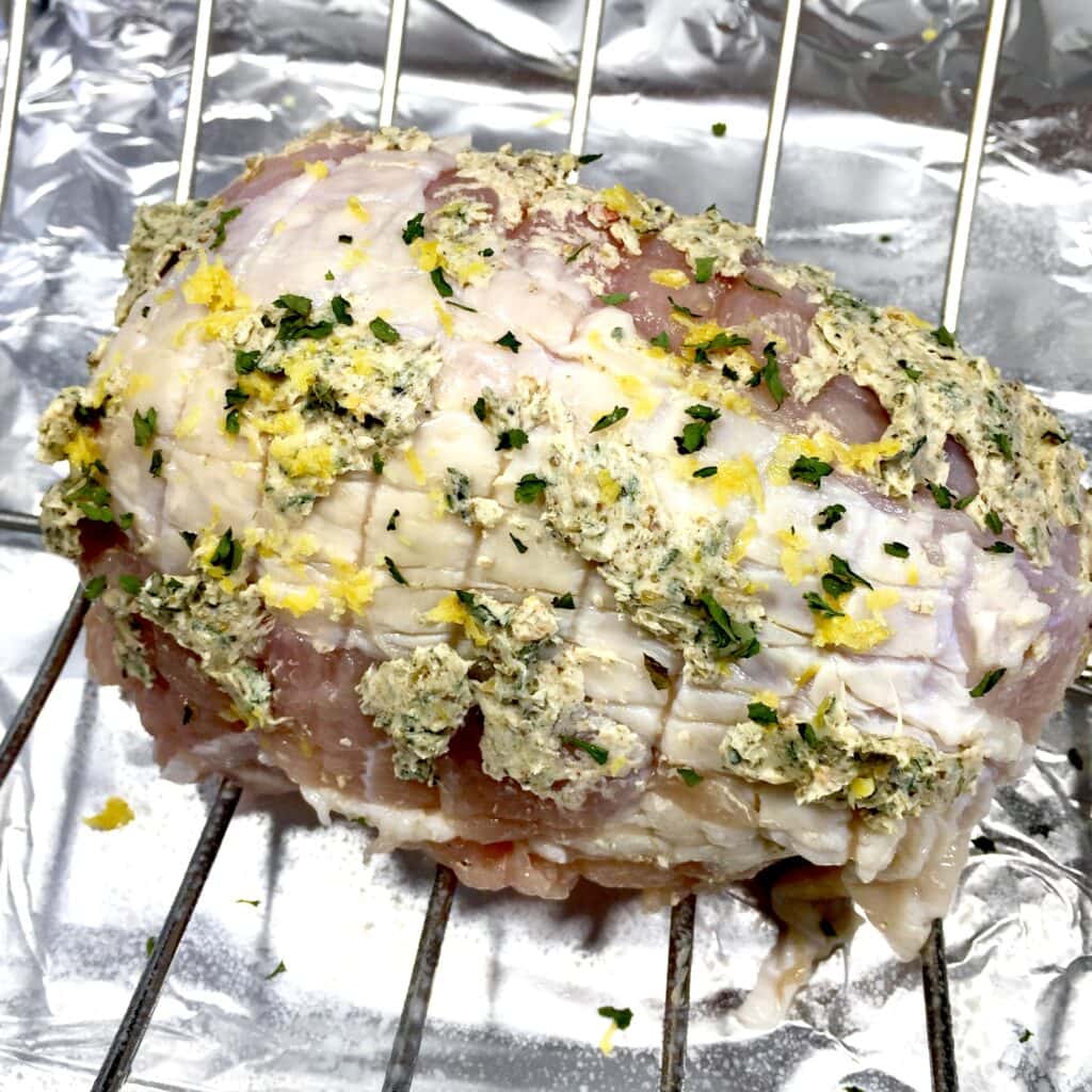 Turkey with herb butter on a rack ready to be roasted