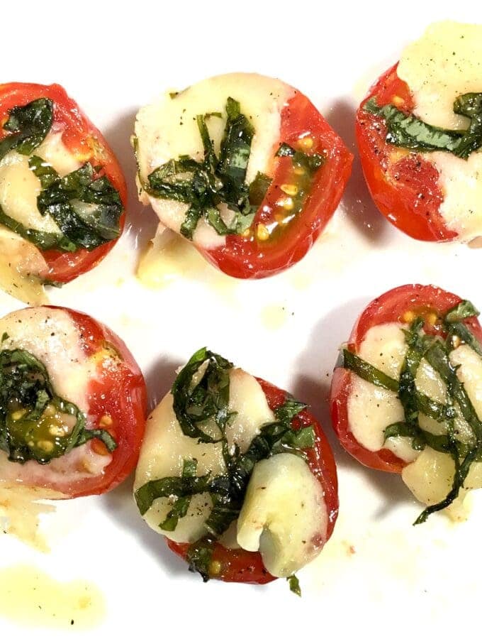 Tomatoes with melted gruyere and basil - Caprese Tomato Bites - on a white plate