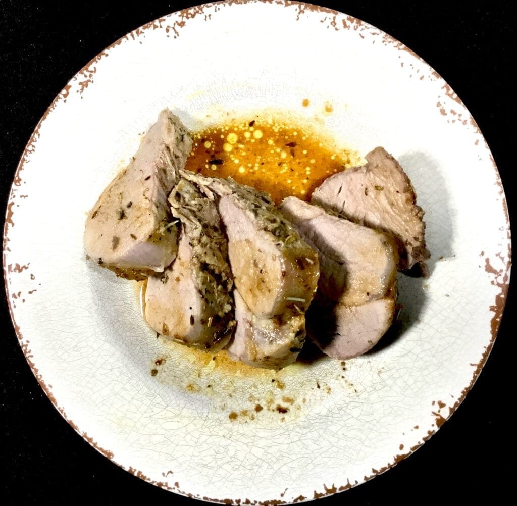 Cooked and sliced pork tenderloin on a white plate