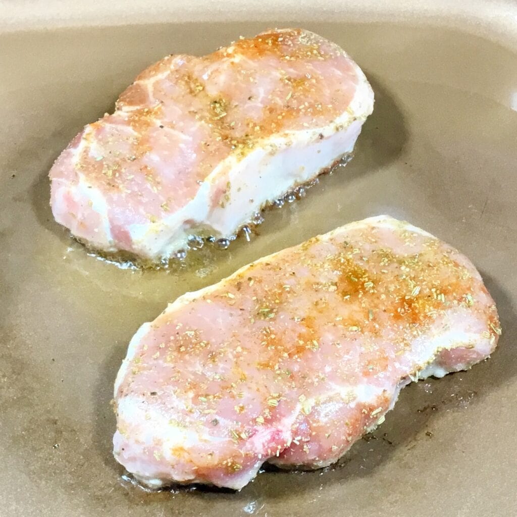 Juicy, restaurant stye pork chops sizzling in a pan.