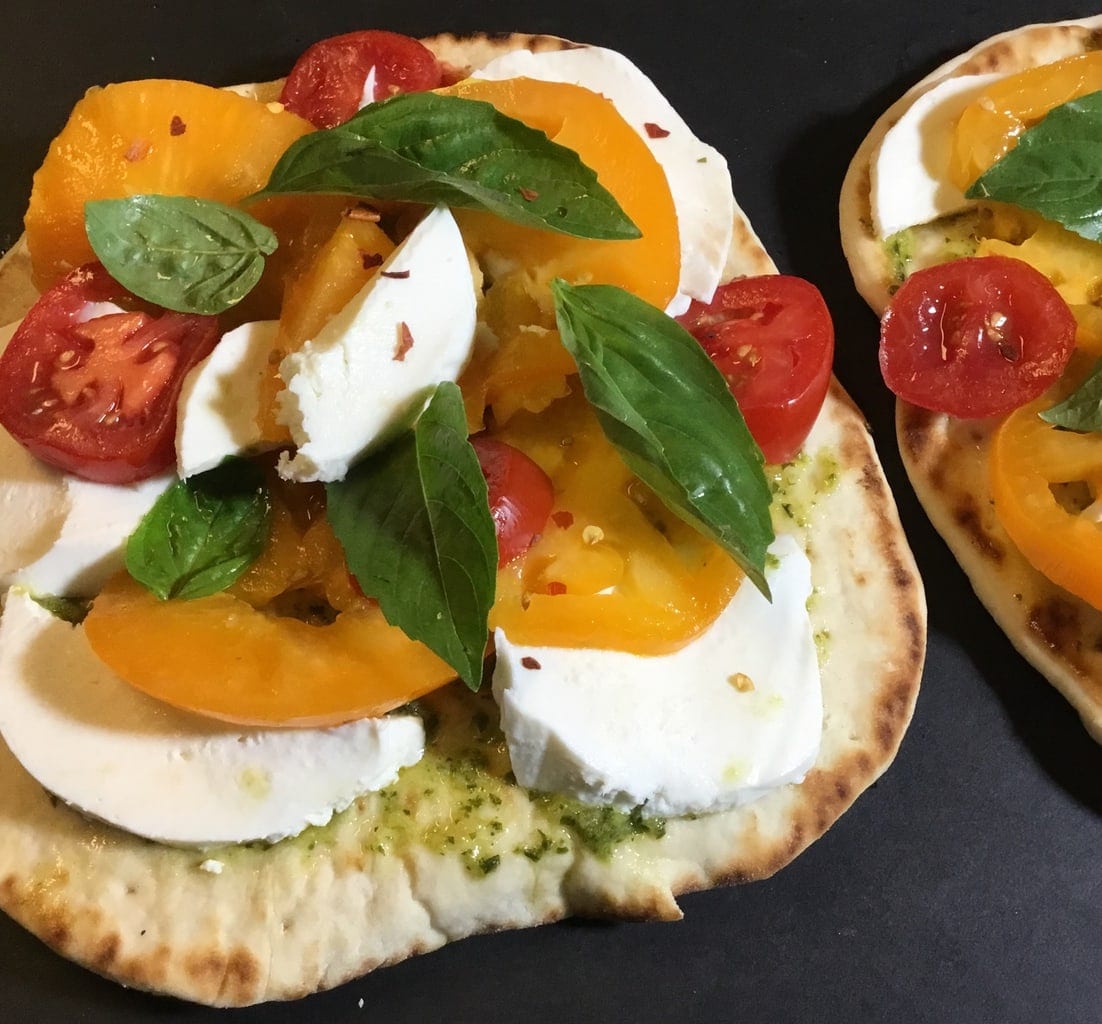 Naan pizza with cheese tomatoes and basil ready to be baked