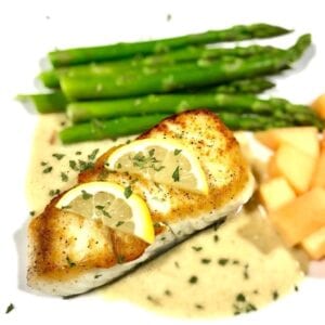 Baked halibut with lemon slices on a bed of tarragon cream sauce