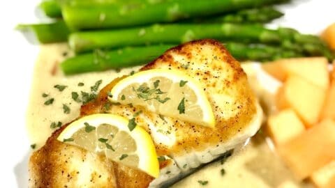 Baked halibut with lemon slices on a bed of tarragon cream sauce