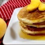 Peach Cobbler Pancakes with dripping syrup on a white plate