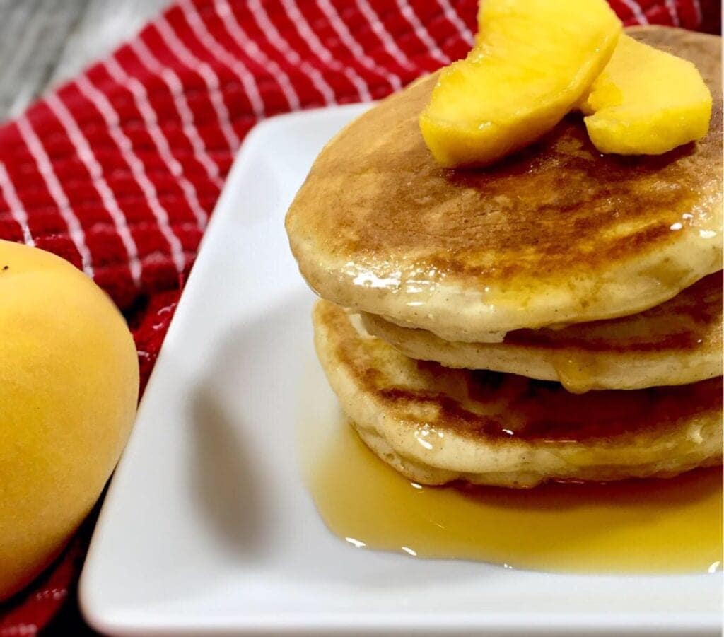 Peach Cobbler Pancakes with dripping syrup on a white plate