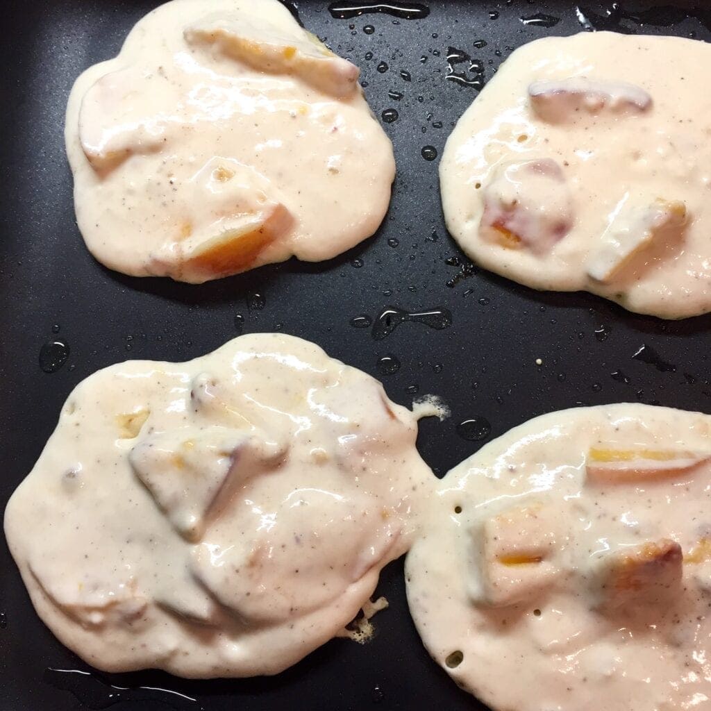 Peach Cobbler Pancakes cooking on a griddle