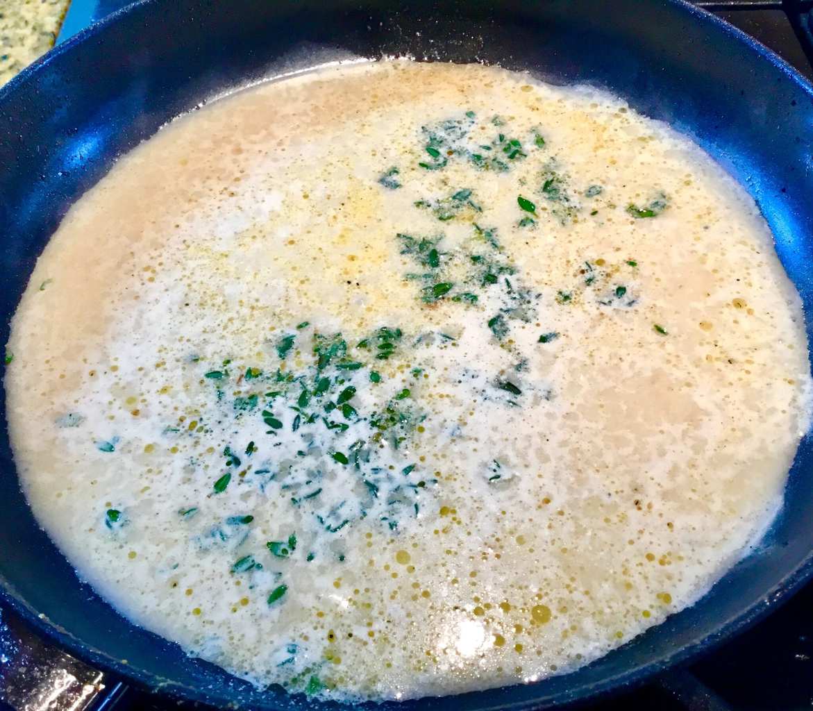 Garlic sauce with fresh thyme simmering on the stove