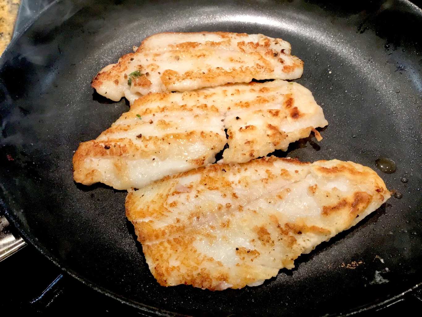 Dover sole fillets cooking in a frypan
