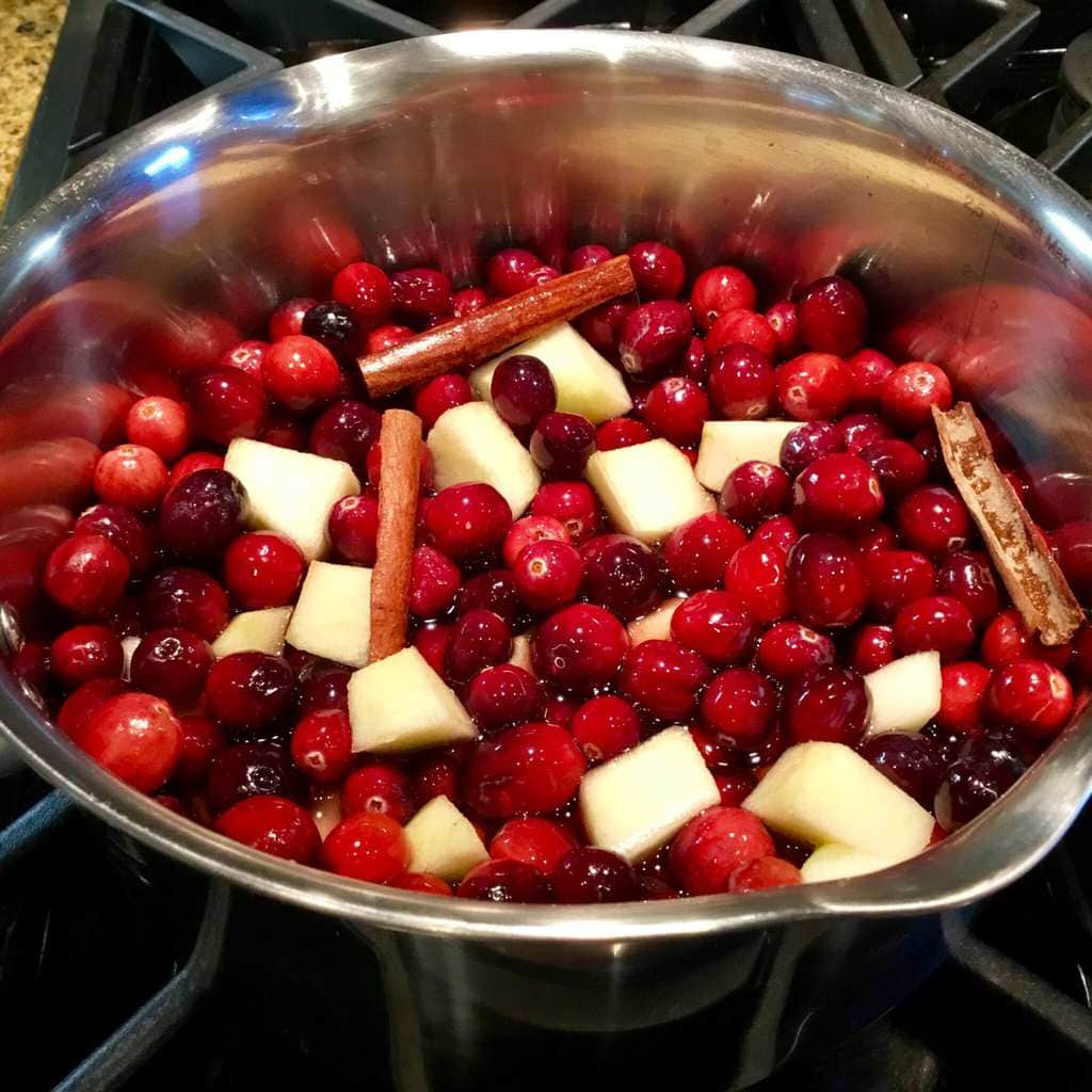 Cranberries, cinnamon sticks and apples cooking on the stove
