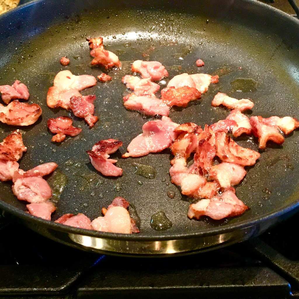 Bacon pieces frying in pan