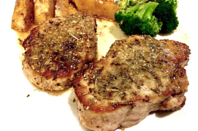 Juicy pork chops, broccoli and sautéed apples on a white plate